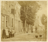 221000 Gezicht in de Leeuweringerstraat met bebouwing en loofbomen te Oudewater; met een groepje poserende kinderen.